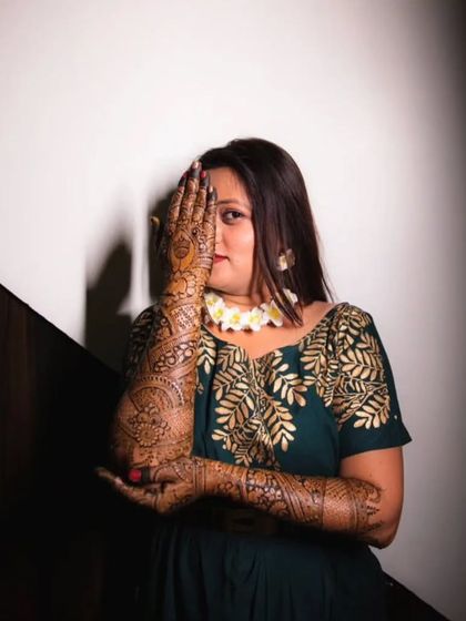A happy client peeking through her beautifully done bridal mehendi.
