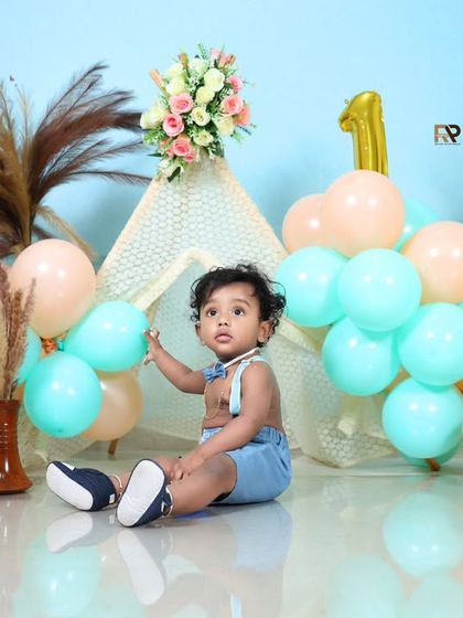 A similar setup with a different angle, showing the baby boy sitting happily among the balloons and props. The soft lighting and pastel colors create a beautiful and timeless portrait.