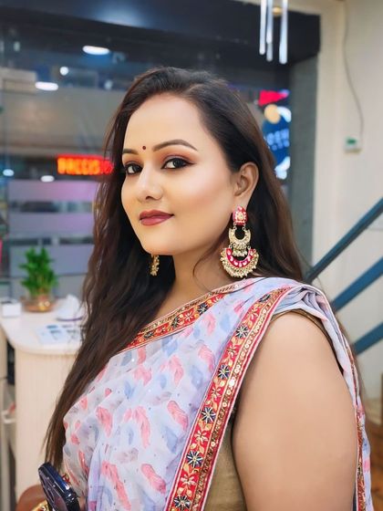 A client ready for a party in a beautiful printed saree. The makeup features warm-toned eyeshadow and a matching lip color.
