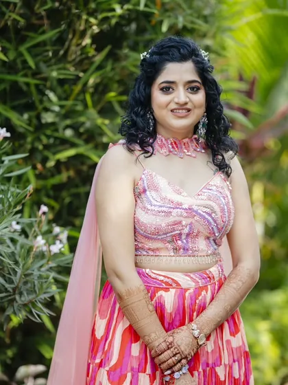 This Haldi hairstyle features natural curls in a half-updo, adorned with a small floral accessory. It's a fun, fresh, and practical style that keeps the hair managed during the ceremony.