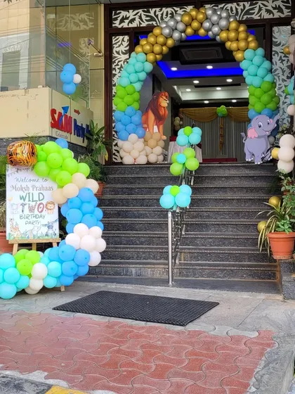 The grand entrance to a jungle-themed birthday party. A colorful balloon arch with lion and elephant cutouts welcomes guests up the stairs to the celebration.
