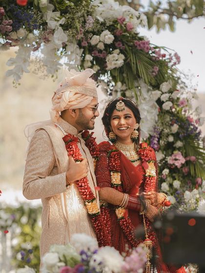A classic, happy portrait of the couple right after their Jaimala exchange, surrounded by a beautiful floral arch.