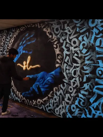 Another view of the calligraffiti mural in progress. This shot shows me adding the final glowing signature, the finishing touch that brings the whole piece together.