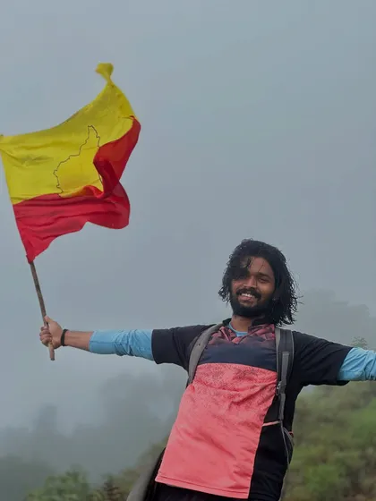 A trekker proudly waves the Karnataka flag at the summit of Gangadikal.