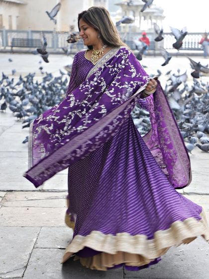 A candid, joyful shot of our purple bandhani-style lehenga. The movement of the skirt and the vibrant color create a beautiful, lively image.