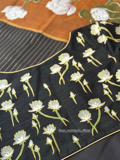 The back of the black blouse, with painted lotuses scattered across the fabric.