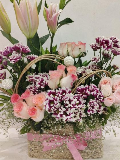 An elegant and structured floral arrangement for Mother's Day. This basket features beautiful pink roses and carnations, with decorative loops adding a touch of modern artistry.