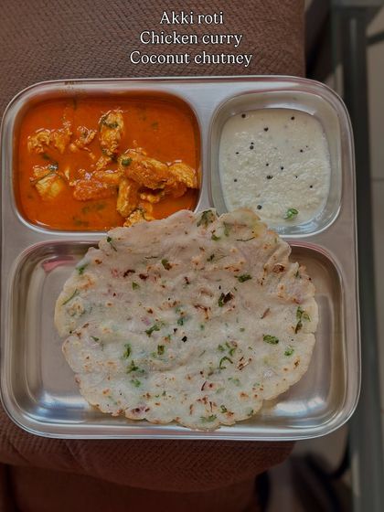 A traditional and delicious meal of akki roti (rice flour flatbread) served with chicken curry and coconut chutney.
