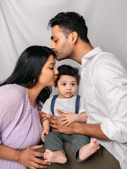 A loving family portrait. The parents' adoring kisses and the baby's curious gaze towards the camera make this a perfectly balanced and emotional shot.
