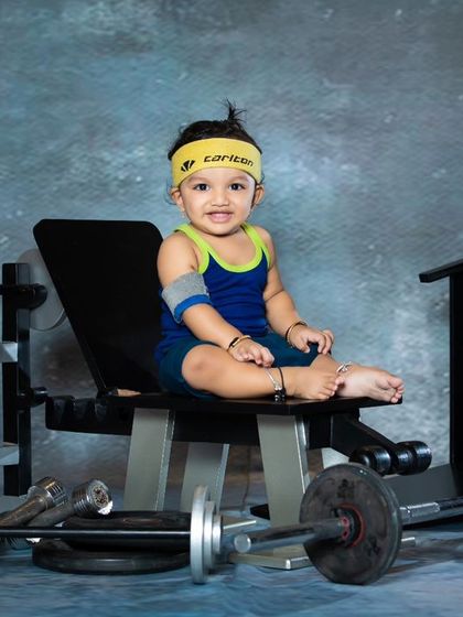 This baby is taking a break on the bench press, looking proud of his workout. The headband and armbands complete the gym-goer look.