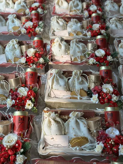 This image shows a large order of wedding return favours ready for dispatch. Each tray is consistently decorated with red and white floral arrangements and contains assorted goodies in potlis, showcasing my ability to handle bulk orders with uniform quality.