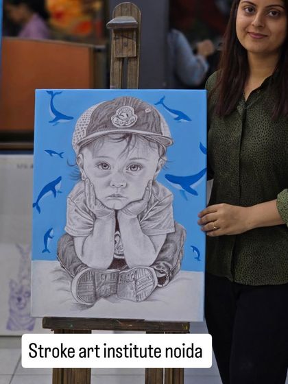 A finished portrait that tells a story. This student proudly presents her ballpoint pen artwork of a young child, where the detailed black and white drawing is set against a vibrant blue background.