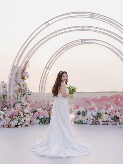 The bride at her dreamy beachside engagement in Bahrain. The pastel floral decor and modern arches perfectly complement the serene ocean backdrop.