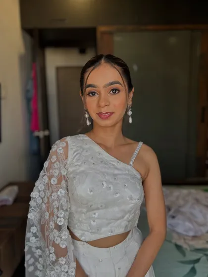 A chic and modern look. The client is wearing an all-white outfit, and her makeup is clean and minimal with a pop of soft pink on the eyes.