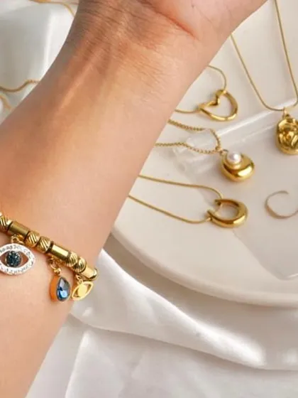 A close-up of an evil eye charm bracelet, with other necklaces blurred in the background. This highlights a specific, trendy product while still showing its place within a larger collection.