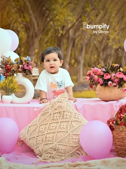 A lovely pink themed picnic setup for an outdoor baby photoshoot. The combination of soft fabrics, flowers, and balloons creates a dreamy scene.