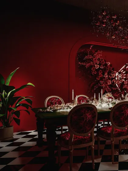 A dining setup within the red-themed restro-bar, featuring a long table set for a banquet. The render captures the dramatic, intimate mood created by the candlelight and floral arrangements.