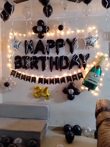 A stylish black and silver themed birthday wall decoration with fairy lights.