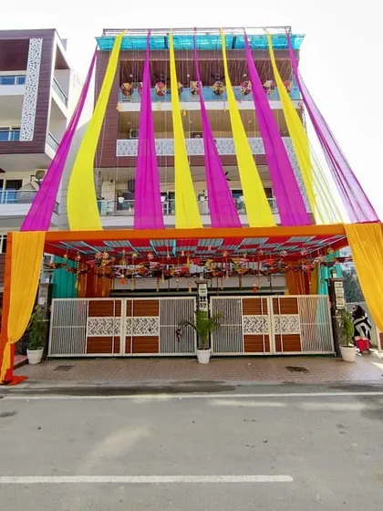 For major home functions, I can transform the entire exterior of a building. This shows a grand entrance tent and facade draping with bright yellow and pink fabrics, creating a festive look for a large ceremony.