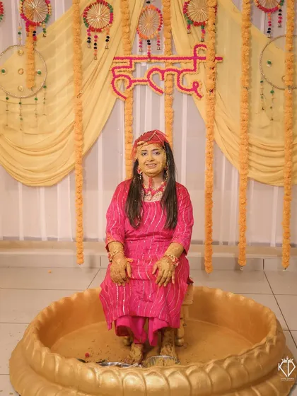 The bride after the Haldi rituals, seated in a traditional tub, smiling through the turmeric paste.