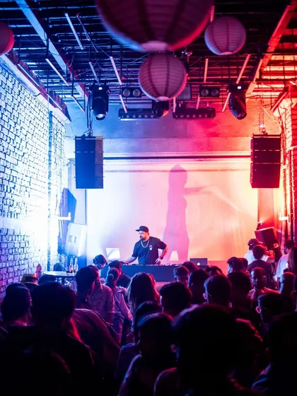 A wide shot of the packed dance floor at Roxy. The red and blue lighting creates an intense, energetic atmosphere.