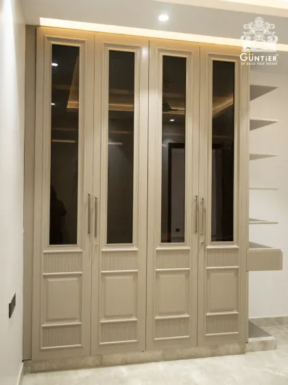 This is what timeless elegance looks like. A custom wardrobe featuring classic paneling and tinted glass doors, built with durable HDHMR and finished to perfection. It’s not just storage; it’s a statement piece for your bedroom.