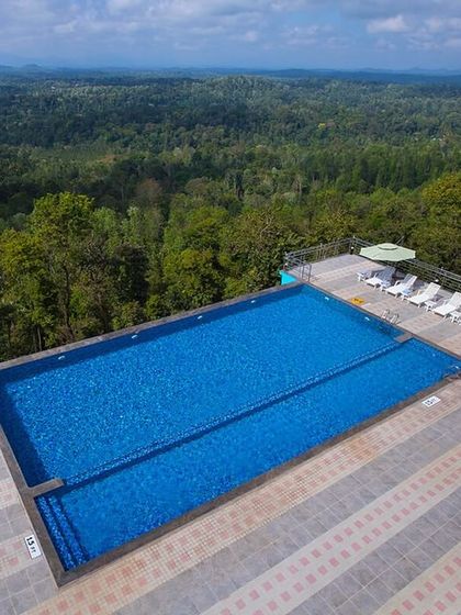 The expansive infinity pool at Coorg Cliffs Resort, overlooking the dense canopy of the Western Ghats.