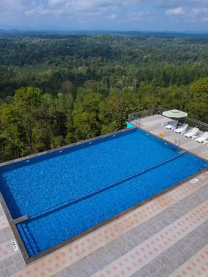 The expansive infinity pool at Coorg Cliffs Resort, overlooking the dense canopy of the Western Ghats.