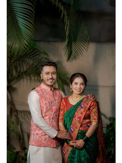 A formal portrait of a couple on their engagement day. The bride is in a beautiful green Paithani saree, and the groom is in a kurta with a stylish pink Nehru jacket.