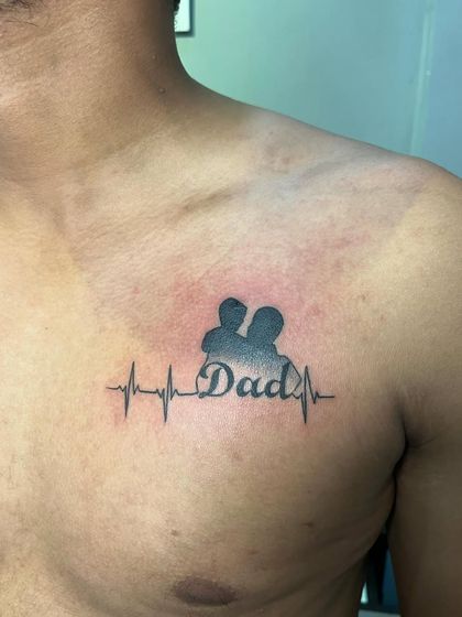 A "Dad" tattoo integrated into a heartbeat EKG line. This design symbolizes that a father's love is the lifeline.