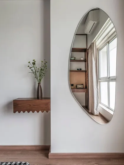 An organically shaped mirror and a scalloped wood floating shelf add a touch of warmth and playful minimalism to this corner in Apartment 1501. These small, custom details are essential for making a compact apartment feel unique and personal.