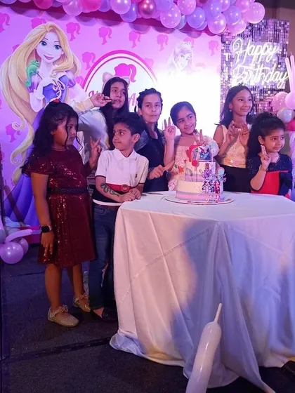 The birthday girl and her friends posing for a cake-cutting photo in front of our Barbie-themed stage.