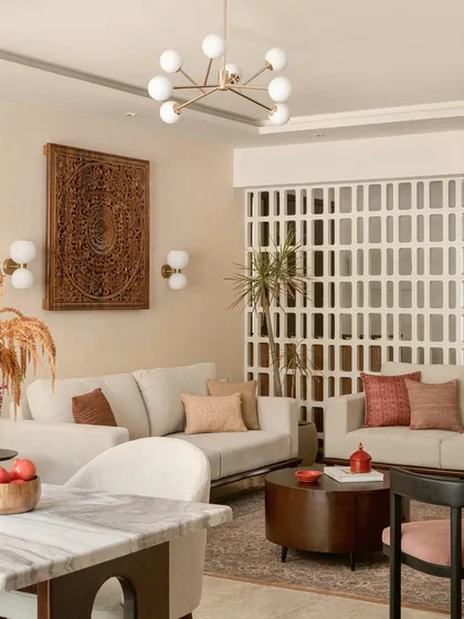 This living room is where modern comfort meets timeless Indian artistry. I anchored the space with a large, hand-carved wooden panel and a delicate jali screen, creating a backdrop that feels both grand and personal. The neutral sofas and contemporary lighting ensure the room remains bright and welcoming, a perfect space for family stories to unfold.