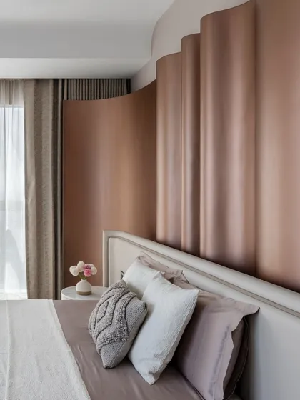 The master bedroom in 'The House of Arcs' features a fluid, curved headboard in a metallic finish, creating a soft, enveloping feel. This space is a perfect example of our approach to quiet luxury, where subtle textures and forms create a harmonious and restful environment.