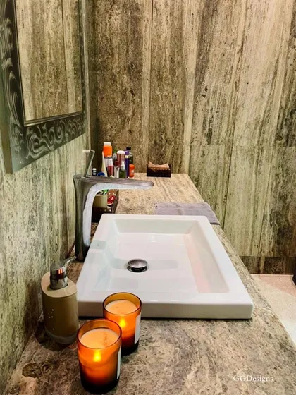 A close-up of the silver travertine marble used in this bathroom. The natural, earthy pattern of the stone adds texture and a sense of calm, complemented by simple decor like scented candles for a spa-like ambiance.
