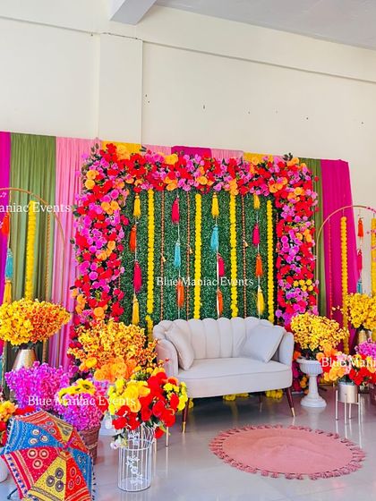 A vibrant angle of the colorful Mehendi setup, showing the abundance of flowers in shades of pink, yellow, and orange that fill the space.