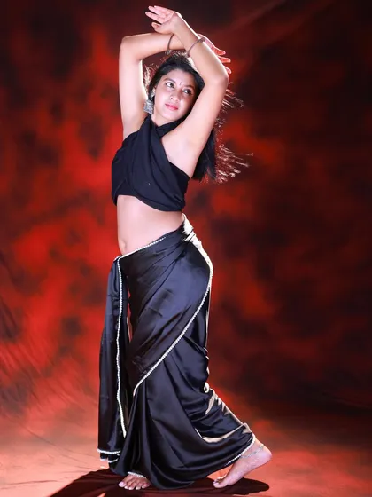 Another dynamic pose, showing the model in motion. The lighting highlights the curves of her body and the flow of the satin saree.