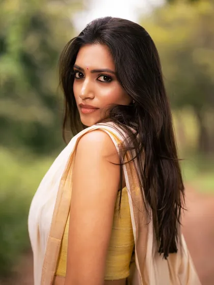 A close-up shot focusing on the model's expressive eyes and the simple beauty of the traditional kasavu saree.