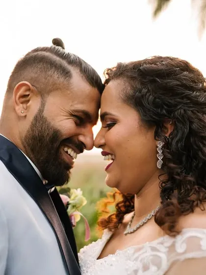 The warm, golden hour light adds to the romance of this candid shot of a newly married couple. The genuine smiles and laughter are what make these wedding portraits so special.