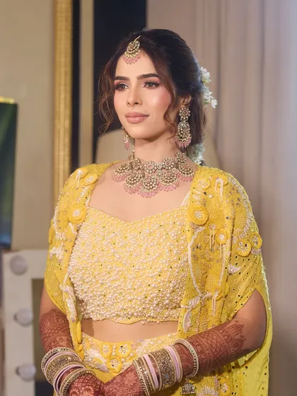 A perfect blend of tradition, glow, and elegance for a Haldi ceremony. This bride's look features soft makeup and a beautiful floral updo.