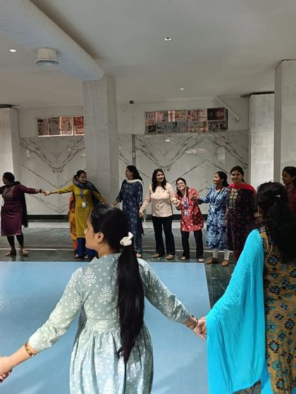 Connection is key. Teachers at Gopalan International School hold hands in a circle, participating in a group activity designed to build trust and a sense of community.