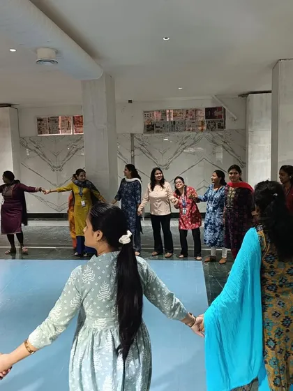 Connection is key. Teachers at Gopalan International School hold hands in a circle, participating in a group activity designed to build trust and a sense of community.