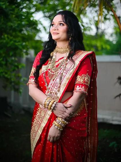 A classic pose showing the intricate details of her traditional jewelry and the rich color of her red saree, enhanced by timeless makeup.