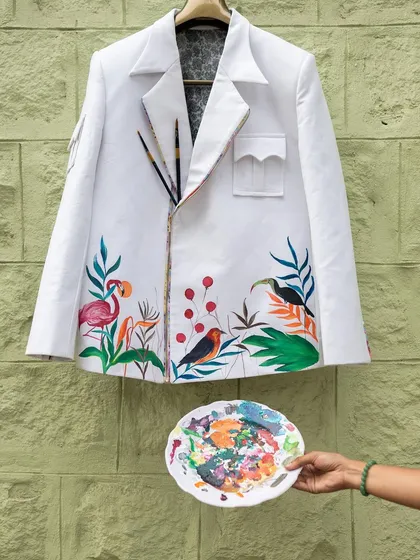 The finished forest-themed jacket, complete with my paint palette. The design features a variety of birds and plants, creating a vibrant and cohesive scene.