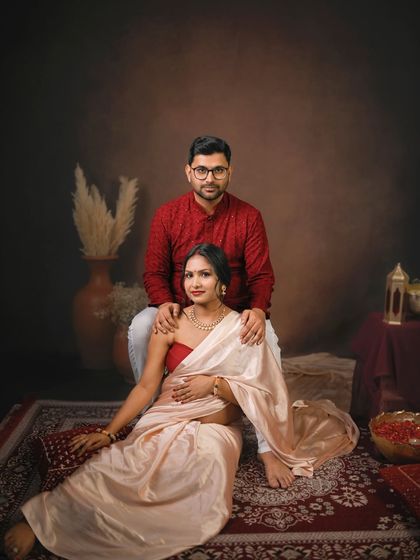 An elegant portrait of an expecting couple in a beautifully styled traditional setting. The earthy tones and classic attire create a timeless and regal feel.