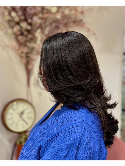 A side view of a classic layer cut on medium-length hair. The layers add shape and volume, and the hair is styled with a slight inward curve at the ends.