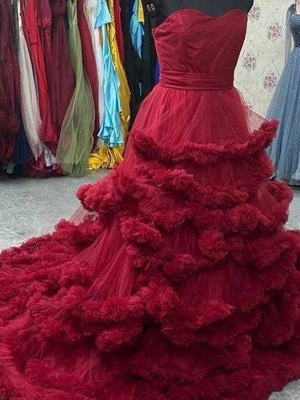 Another angle of the wine-red ruffled gown, showcasing its dramatic silhouette from the side.