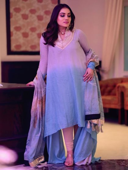 A poised and elegant standing pose. This shot captures the flowing fabric and asymmetrical design of the beautiful traditional outfit.