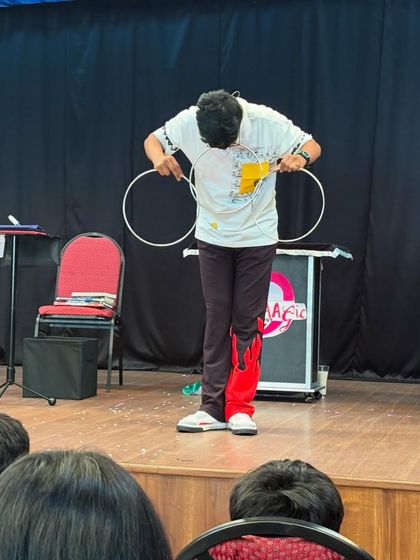 A young magician performs the classic linking rings trick for an engaged audience. Our workshops sometimes even give kids the chance to learn a trick or two.