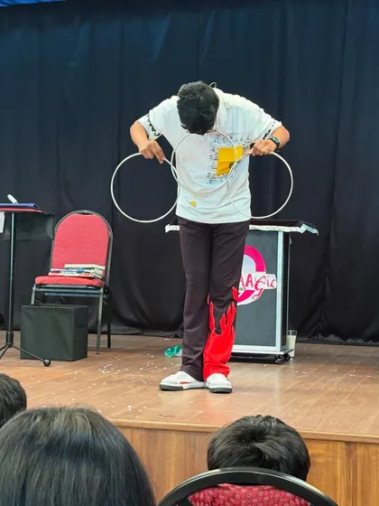 A young magician performs the classic linking rings trick for an engaged audience. Our workshops sometimes even give kids the chance to learn a trick or two.